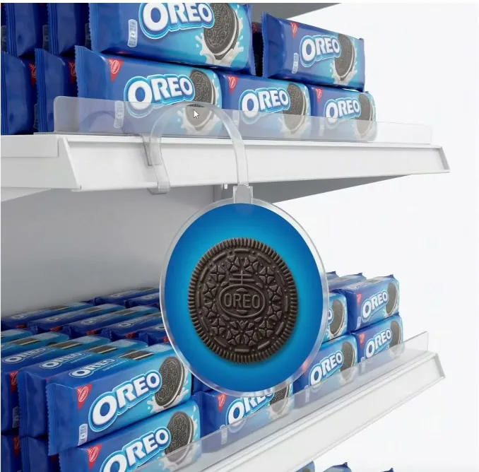 Wobbler redondo azul de Oreo de Bellto colgado de un brazo transparente delante de una balda con paquetes de galletas