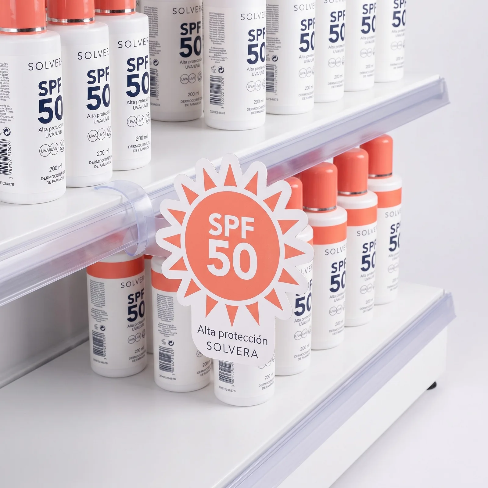Sun-shaped Solvera cardboard wobbler with SPF 50, on its clear arm in front of the bottles