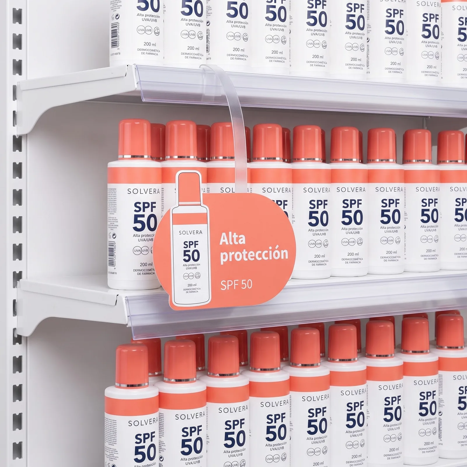 Oval coral Solvera wobbler with a die-cut bottle and the words Alta protección, on its flexible arm
