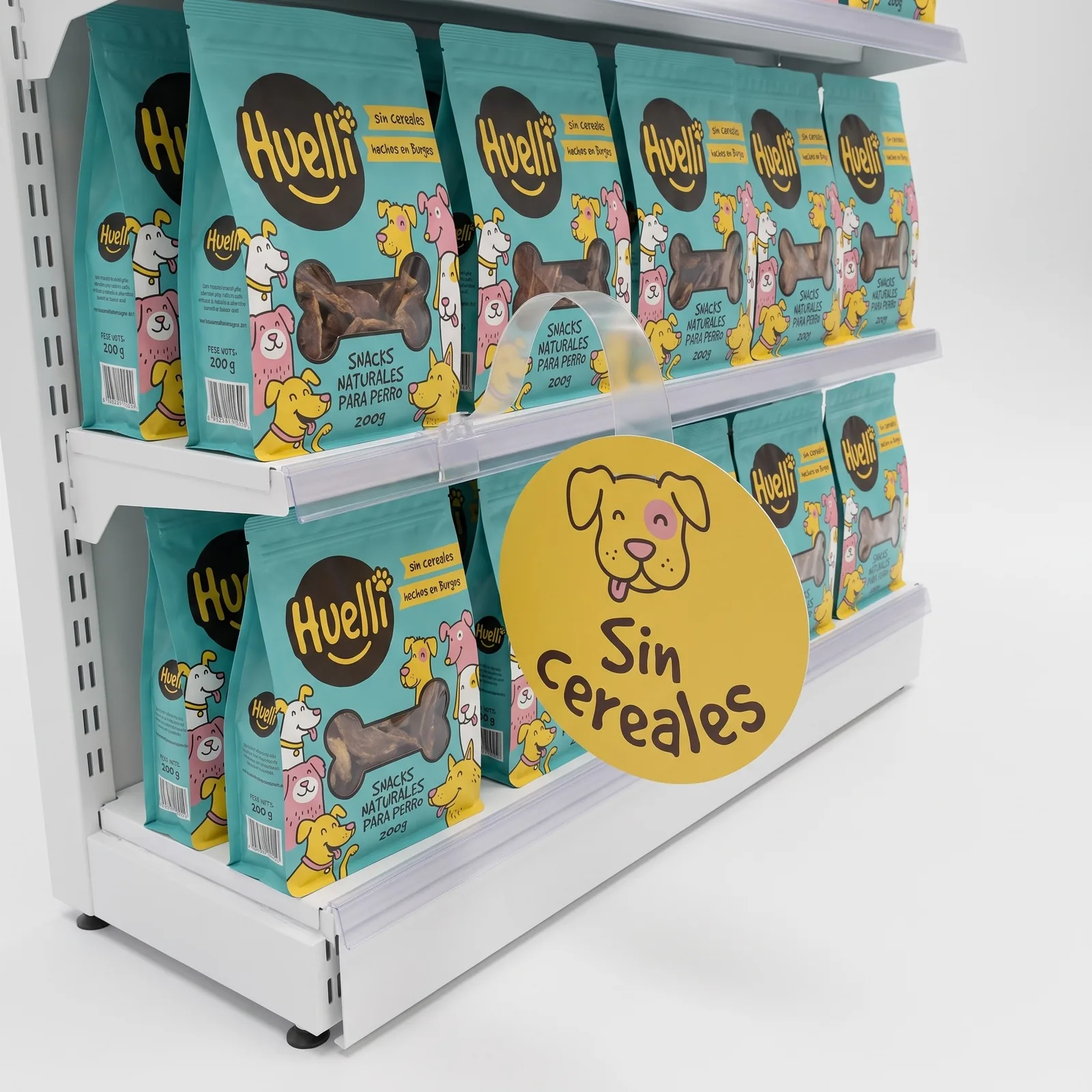 Wobbler redondo amarillo de Huelli con la cara de un perro ilustrado y el texto Sin cereales, en su brazo flexible