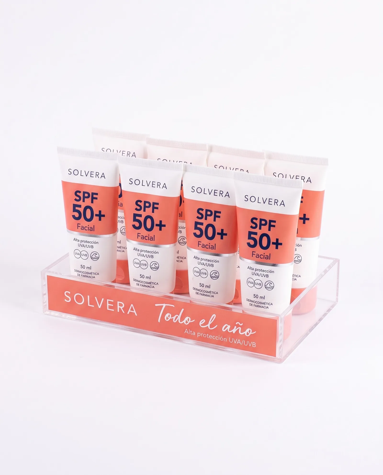 Bandeja de mostrador de metacrilato transparente de Solvera con un frontal coral con el logo y Todo el año, y ocho tubos de protector solar facial
